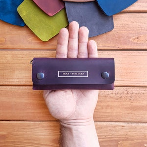 May include: A burgundy leather key holder with a silver snap closure and a rectangular label that says "TEXT - INITIALS".