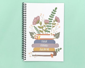 May include: A white spiral bound journal with a floral design and the text "Book Review Journal".