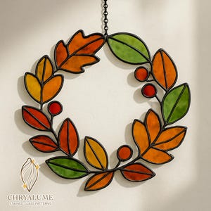 Può includere: Ghirlanda in vetro colorato con foglie autunnali nei toni dell'arancione, giallo e verde, e bacche rosse. La ghirlanda è delineata in nero e appesa a una catena. Il logo "CHRYALUME STAINED GLASS PATTERNS" è in basso.