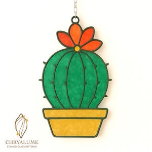 Op de afbeelding: Een glas-in-lood cactus met een felgroen lichaam, een oranje en rode bloem en een gele pot. De cactus heeft donkergroene contouren en wordt opgehangen aan een metalen ketting. Ontwerp van Chryalume Stained Glass Patterns.