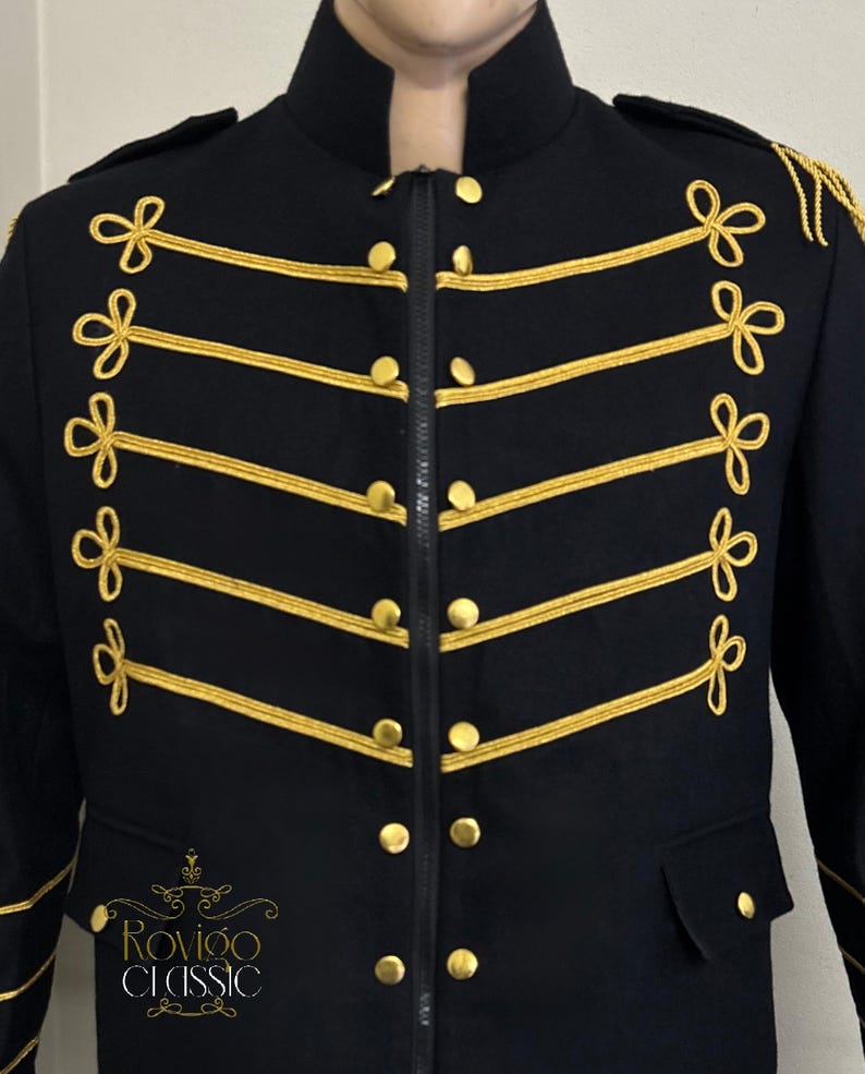 May include: A black military-style jacket with gold trim and buttons. The jacket has decorative gold rope detailing across the chest and shoulders. It features a high collar and a zip closure. The brand name "Rovigo Classic" is visible on the lower left.