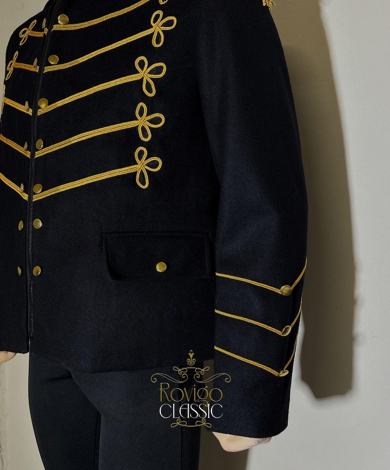 May include: Black military-style jacket with gold trim and buttons. The jacket has gold embroidery on the front and sleeves, and a small pocket. Part of the Rovigo Classic collection. The jacket is a classic design.