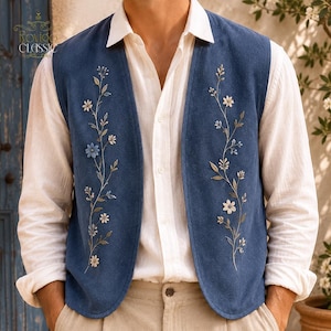 Könnte beinhalten: Eine blaue Weste mit zarter weißer und hellblauer Blumenstickerei auf den Vorderteilen, getragen über einem weißen Hemd mit Knopfleiste und einer hellen Hose. Die Weste hat eine glatte Textur und ein schlichtes, ärmelloses Design.