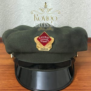 May include: A dark green military-style cap with a black visor and a gold badge that reads "Railway Express Agency" and "Your ID".