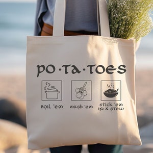 May include: A white canvas tote bag with the text "PO-TA-TOES" in black. The bag has three illustrations of cooking methods for potatoes: boiling, mashing, and stewing.