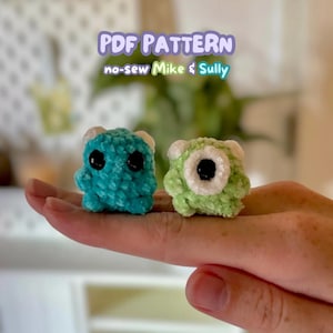 Puede incluir: Se muestran dos pequeñas figuras de monstruos de ganchillo, una turquesa y otra verde. El monstruo turquesa tiene dos ojos negros, y el monstruo verde tiene un ojo negro. El texto "PDF PATTERN no-sew Mike & Sully" está encima de las figuras.