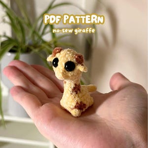 Könnte beinhalten: Ein kleines, ohne Nähen gefertigtes Giraffenplüschtier mit gelbem Körper und braunen Flecken. Die Giraffe hat große schwarze Augen und kleine Ohren. Der Text auf dem Bild lautet "PDF PATTERN" und "no-sew giraffe".