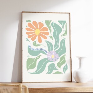 May include: A framed print with a floral design featuring orange, green, and purple flowers. The text "Love And Gratitude" is written in blue on the print.