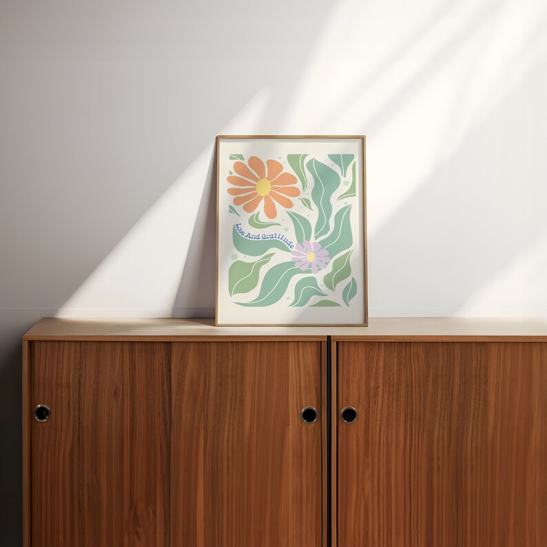 May include: A framed print with a floral design featuring orange and purple flowers with green leaves. The print has the text "Love And Gratitude" in a light blue font.