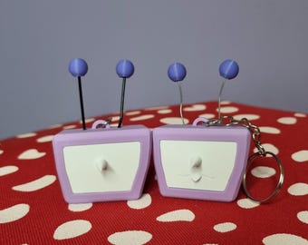 Llavero inspirado en Tenna con cara intercambiable, accesorio personalizable con cabeza de TV y antenas flexibles.