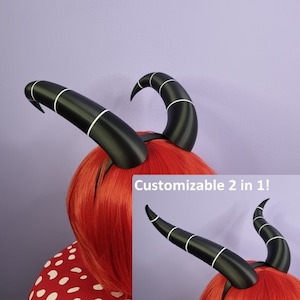 Op de afbeelding: Zwart-witte duivelshoorn haarband met aanpasbare opties. De haarband wordt gedragen door een persoon met rood haar. De tekst "Customizable 2 in 1!" is zichtbaar in de afbeelding.