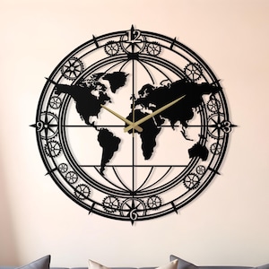 Pode incluir: Um relógio de parede de metal preto com um design de mapa-múndi. O relógio é circular, com detalhes em forma de engrenagens e ponteiros dourados. Está montado numa parede clara acima de um sofá cinzento. Diâmetro: cerca de 76 cm.