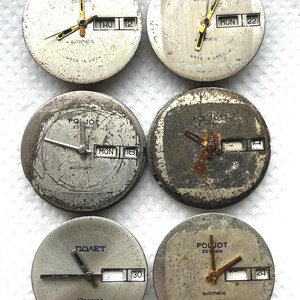 May include: Six vintage watch faces with visible wear and tear. The faces are round, with gold-toned hands and markers. Some display the day and date. The text "POLJOT" and "automatic" are visible on some faces. The text "MADE IN USSR" is also visible.
