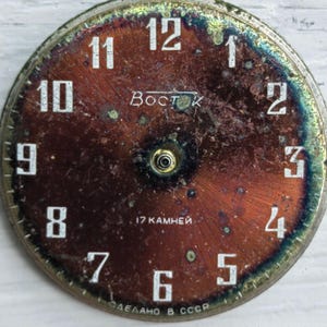 May include: Vintage watch face with a distressed, reddish-brown dial. White numerals mark the hours, with the brand name "Восток" and the text "17 камней" visible. The words "СДЕЛАНО В СССР" are also present.