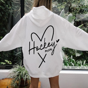 May include: White hoodie with a black heart and the text "Hockey Mom" with crossed hockey sticks inside the heart.