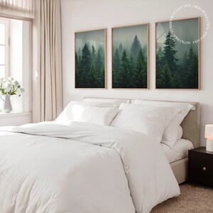 K&ouml;nnte beinhalten: Ein wei&szlig;es Bett mit einem wei&szlig;en Bettbezug und zwei wei&szlig;en Kissen. Drei gerahmte Drucke einer nebeligen Waldszene h&auml;ngen an der Wand hinter dem Bett.