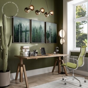 K&ouml;nnte beinhalten: Ein Heimb&uuml;ro mit einer gr&uuml;nen Wand, einem Holzschreibtisch mit einem Laptop, einer Kaktuspflanze und einem gr&uuml;nen B&uuml;rostuhl. Der Schreibtisch hat einen Satz von drei gerahmten Drucken einer nebeligen Waldszene.