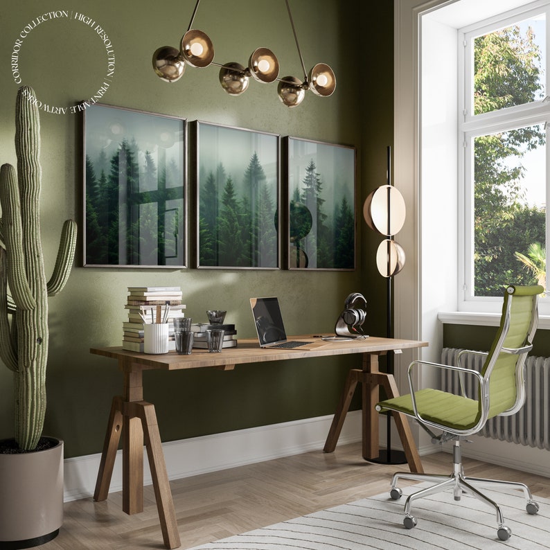 K&ouml;nnte beinhalten: Ein Heimb&uuml;ro mit einer gr&uuml;nen Wand, einem Holzschreibtisch mit einem Laptop, einer Kaktuspflanze und einem gr&uuml;nen B&uuml;rostuhl. Der Schreibtisch hat einen Satz von drei gerahmten Drucken einer nebeligen Waldszene.