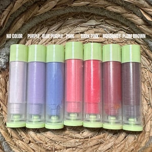K&ouml;nnte beinhalten: Eine Sammlung von Lippenbalsam in transparenten Tuben mit hellgr&uuml;nen Kappen. Die Balsame sind in verschiedenen Farben erh&auml;ltlich, darunter Lila, Rosa und Burgunderrot. Der Text &uuml;ber den Balsamen lautet "NO COLOR, PURPLE, BLUE PURPLE, PINK, DARK PINK, BURGUNDY, PLUM BROWN."
