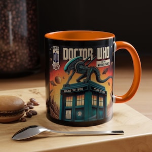 Puede incluir: Taza de cerámica negra con interior y asa naranja. La taza presenta un diseño de estilo cómic con las palabras "Doctor Who" y una ilustración de un alienígena en una TARDIS. Una cuchara y un macaron están sobre la superficie de madera.