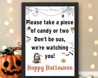 May include: A framed Halloween sign with the text "Please take a piece of candy or two. Don't be sus, we're watching you! Happy Halloween." The sign features illustrations of spiders, bats, and a ghost.