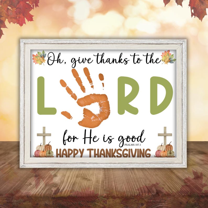 May include: A framed Thanksgiving print with a white border. The print features the words "Oh, give thanks to the LORD for He is good" with a handprint and pumpkins. The words "Happy Thanksgiving" are also included.