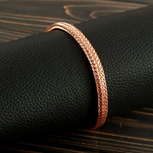 May include: A rose gold bracelet with a braided chain design.