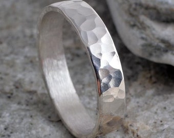 May include: A silver hammered band ring. The ring is smooth on the inside and has a hammered texture on the outside.