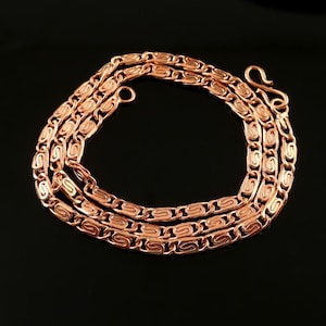 May include: A copper chain necklace with a detailed, intricate design. The chain is made of small, linked loops that create a textured, woven look.