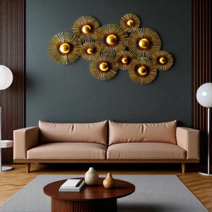 May include: A modern living room featuring a beige sofa, a round wooden coffee table, and a gray rug. Above the sofa, a cluster of gold metal wall art with sunburst designs adds a decorative touch. The wall is painted a dark teal color.
