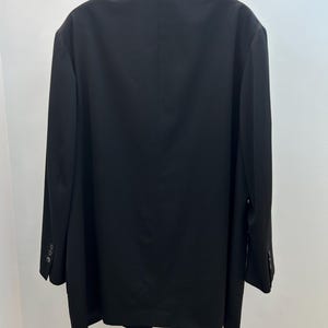 May include: A black blazer hanging on a wooden hanger. The blazer has a classic design with a notched lapel and three buttons on each cuff. The back of the blazer is smooth and tailored, with a single vent.