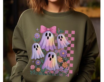 May include: Olive green sweatshirt featuring a colorful graphic of four cartoon ghosts with pastel rainbow coloring, a pink bow, and flowers. The design includes a pink and white checkered pattern. A fun and whimsical design.