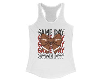 May include: White racerback tank top with a brown football bow graphic and the words "GAME DAY" in a stacked design. The text is in a mix of black and red, with a football-themed bow in the center.
