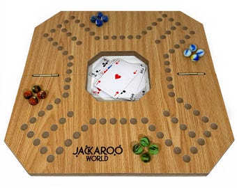 May include: A wooden Jackaroo board game with a light brown finish. The board has a central card holder with playing cards, and is surrounded by holes for marbles. Marbles in blue, green, and red-brown are scattered on the board. The game's logo is printed on the board.