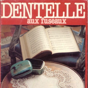 May include: A vintage book cover with the title "DENTELLE aux fuseaux" in white letters on a red background. The image features a lace doily, a small painted box, and an open book with sheet music.