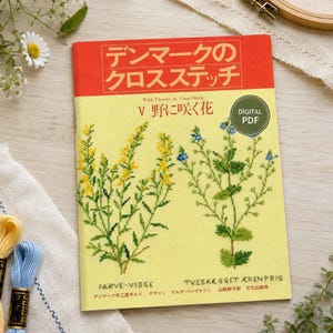 以下が含まれることがあります： 「デンマークのクロスステッチ」と題されたデジタルPDFクロスステッチ図案集。黄色い表紙には黄色と青の野草のイラストが描かれており、「Wild Flowers in Cross-Stitch V」という英語のタイトルと日本語の文字が記載されています。