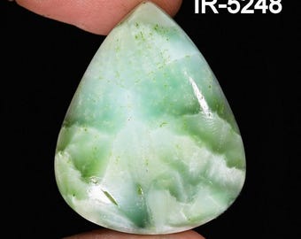 May include: A pear-shaped gemstone with a mix of light green and white hues. The stone has a polished surface with a marbled appearance. The text "IR-5248" is displayed in white, upper-case letters on the upper right side of the image. The gemstone is held between two fingers.