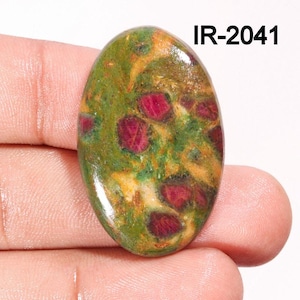 Könnte beinhalten: Ovaler Cabochon-Edelstein mit einem grünen, gelben und roten Muster. Der Stein hat eine polierte Oberfläche und ist in einem Silberring gefasst. IR-2041