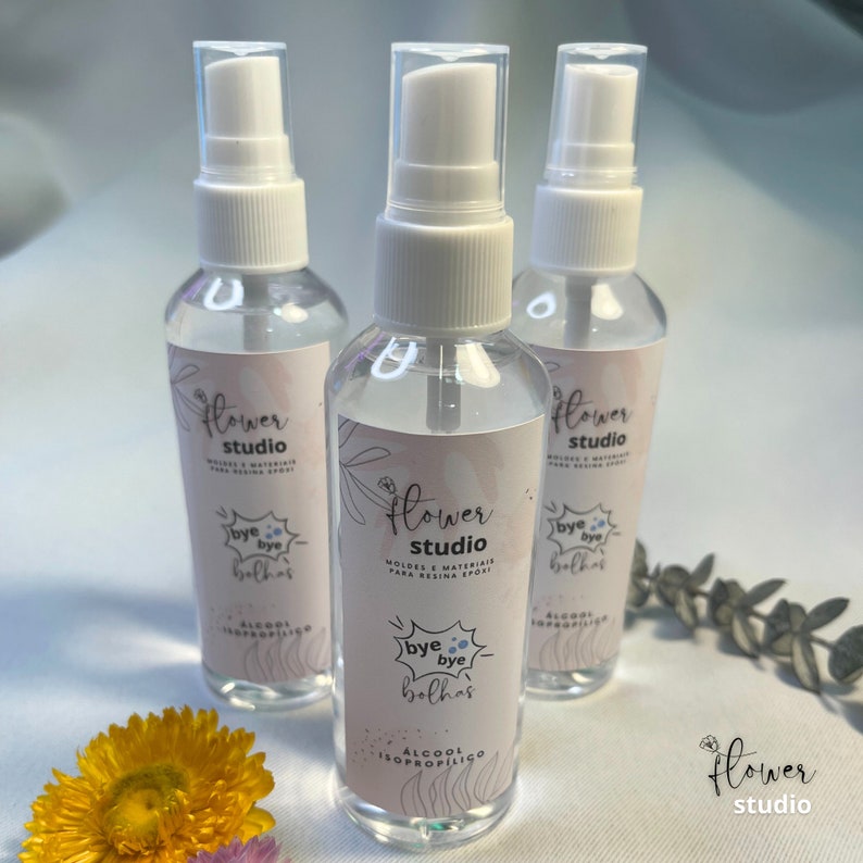 Puede incluir: Tres botellas de pl&aacute;stico transparente con pulverizadores blancos y etiquetas. Las etiquetas son rosas y blancas con el texto "Flower Studio" y "Bye Bye Bolhas" en portugu&eacute;s. Las botellas contienen alcohol isoprop&iacute;lico.