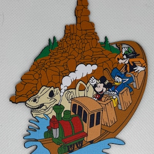 May include: A brown, wooden, cutout of a train ride with Mickey Mouse, Donald Duck, and Goofy. The train is going through a brown, rocky mountain with a green, leafy top. The train is on a blue, wavy water surface.