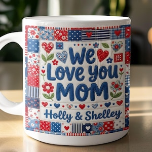 May include: White ceramic mug with a colorful patchwork design featuring red, white, and blue squares, hearts, and floral accents. The mug reads "We Love you MOM" with the names "Holly & Shelley" below.
