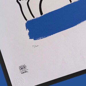 Puede incluir: Impresi&oacute;n enmarcada con fondo blanco, con dibujo lineal negro y pincelada azul. La impresi&oacute;n incluye el texto "121/200" y la firma y el logotipo del artista. La obra de arte es una edici&oacute;n limitada.