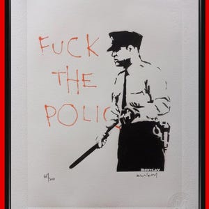 以下が含まれることがあります： 警棒を持った警察官の黒いステンシルイラストが描かれた額装プリント。左側にはオレンジ色のインクでFUCK THE POLICEという文字が書かれています。プリントにはBanksyの署名とエディション番号165/300が含まれています。