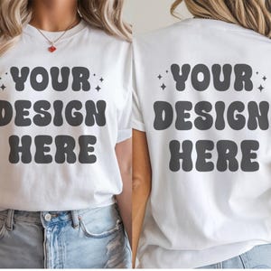 May include: White t-shirt with short sleeves and a crew neck. The front and back of the shirt have the text "YOUR DESIGN HERE" in black, with a retro font.