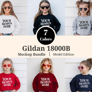 Puede incluir: Un paquete de maquetas con siete sudaderas Gildan 18000B de diferentes colores para niños. Cada niño lleva una sudadera con el texto "YOUR DESIGN HERE". Las sudaderas son de varios colores, incluyendo blanco, negro, gris, rojo y azul marino.