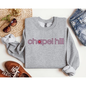 May include: A grey sweatshirt with a red heart and the text "chapel hill" in a burgundy colour.