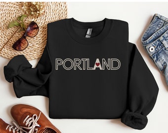 May include: Black sweatshirt with a white outline of the word "PORTLAND" with a red heart in the "A".