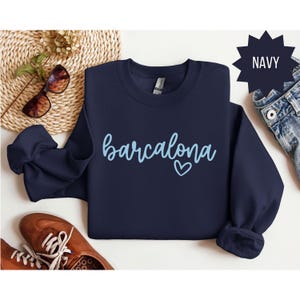 May include: Navy blue sweatshirt with the text "barcelona" in light blue with a small heart.