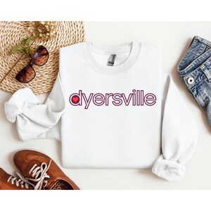 May include: White sweatshirt with a maroon graphic that says "dyersville" with a red heart in the "o".