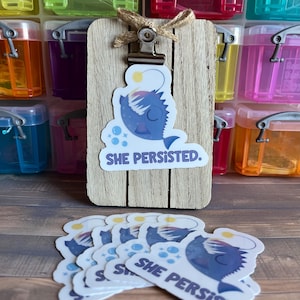 May include: A set of eight stickers featuring a cartoon anglerfish with the text "She Persisted."